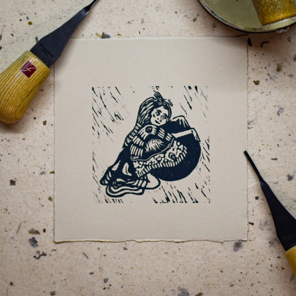 picture of linocut relief print of woman with moth wings hugging sphere, carving tools are on edges
