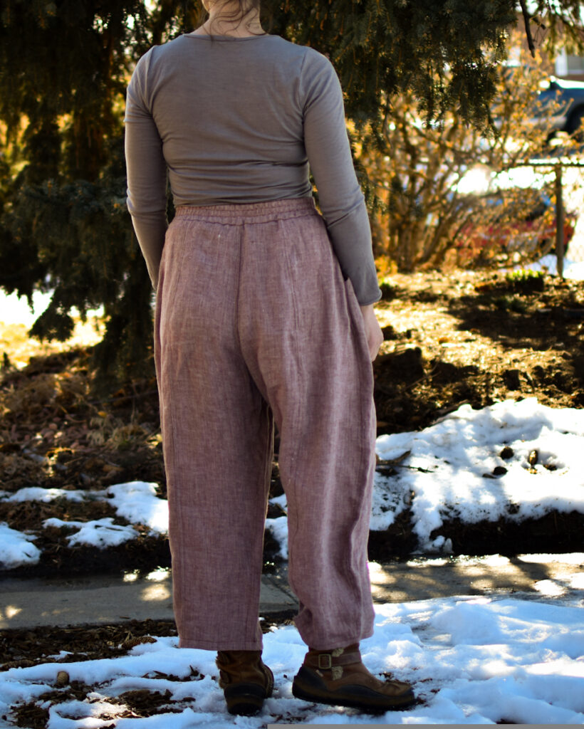 white woman dressed in nutmeg linen twill high waisted wide legged arthur pants and gray shirt. her back is to the camera