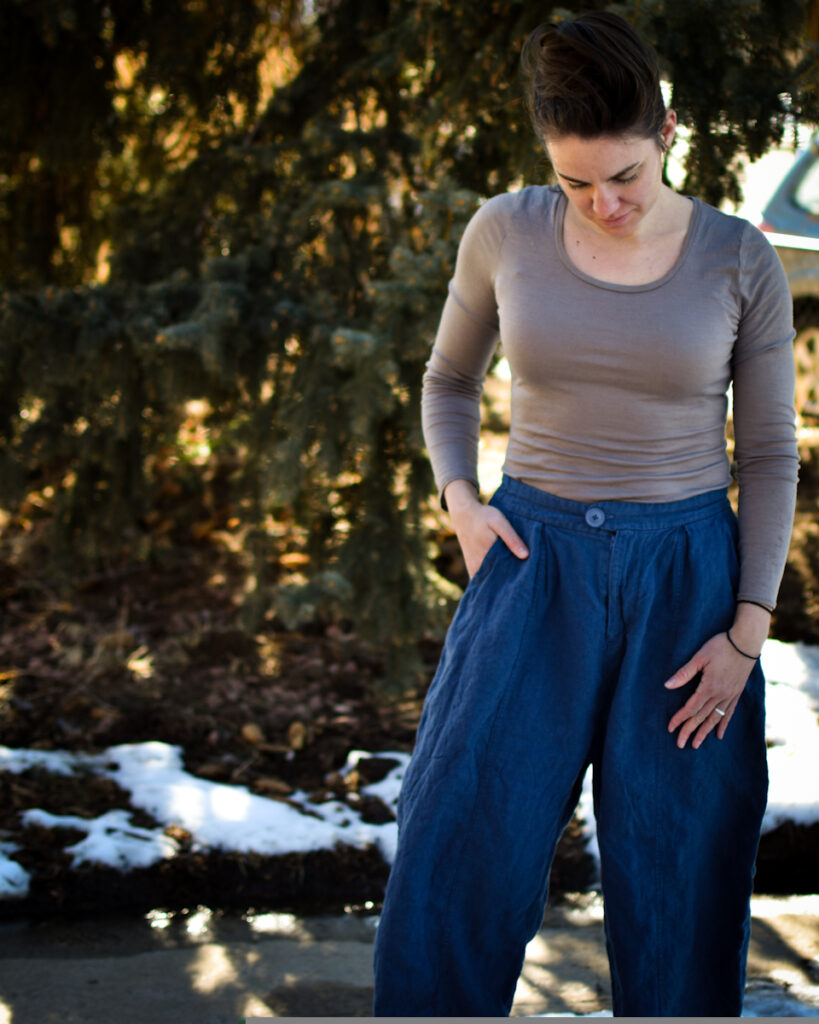 white woman looking down at blue linen high waisted wide legged casual pants and merino wool gray top