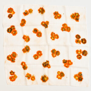 spread out silk scarf with eco-printed coreopsis flowers, showing prints of orange and yellow flowers in groups of 3