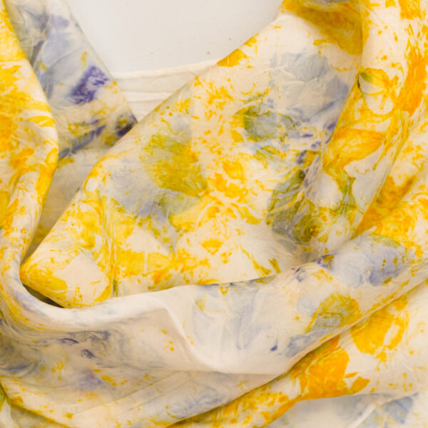 detail of rumpled large silk square scarf with scattered yellow and purple, and petal images on white background. made with natural dye technique